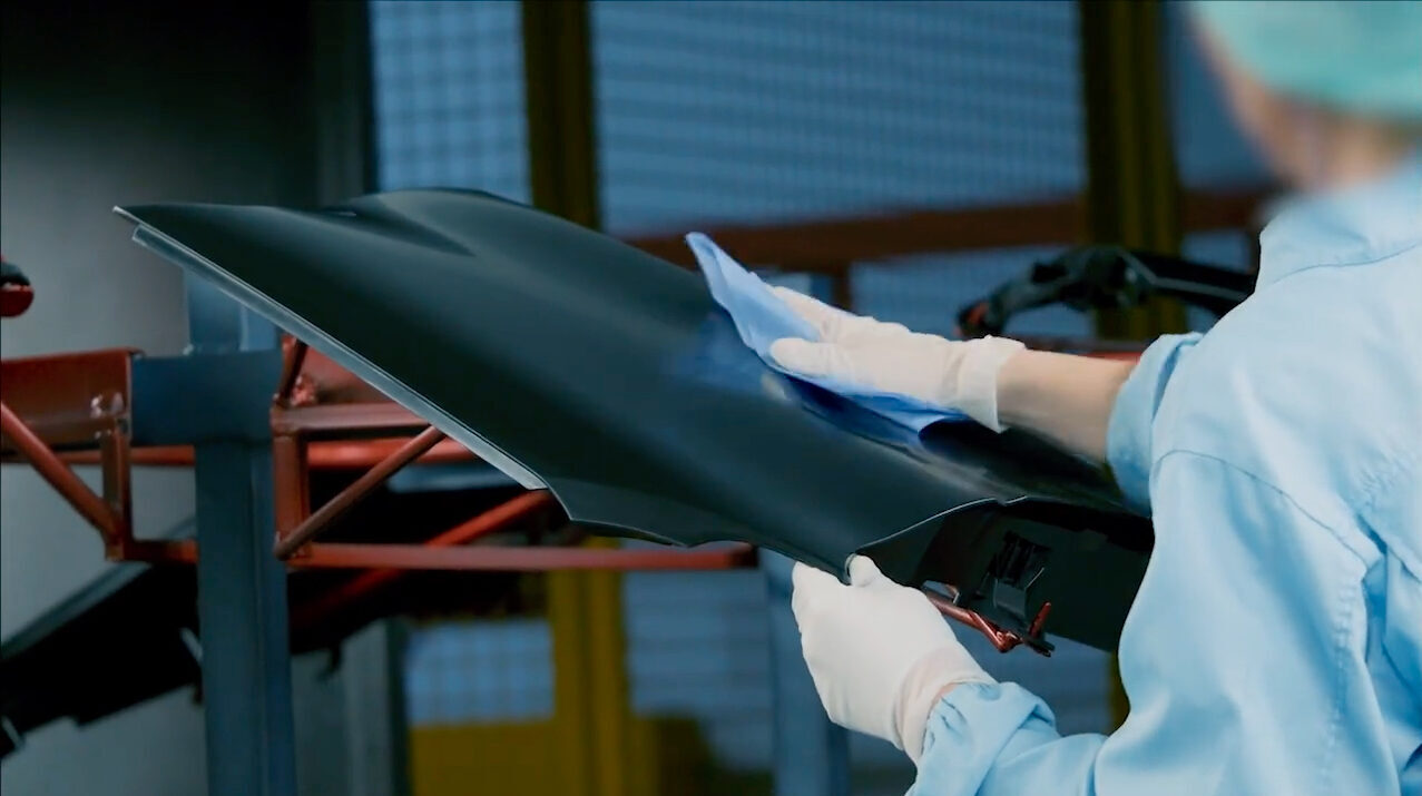 A factory worker cleaning a car panel with a Gekatex wipe